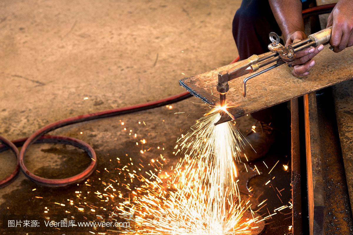 在生产厂用电火花切割金属板材的工人。